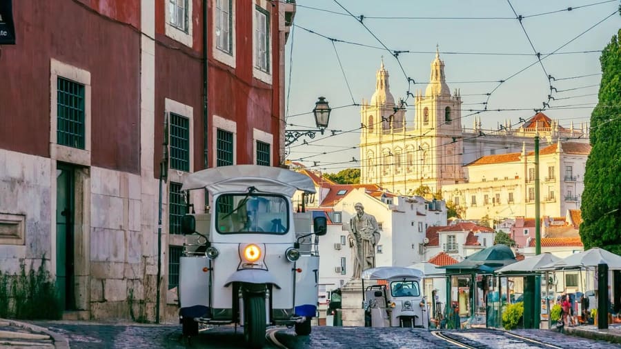 A David Tours tuk-tuk on an Alfama street at golden hour